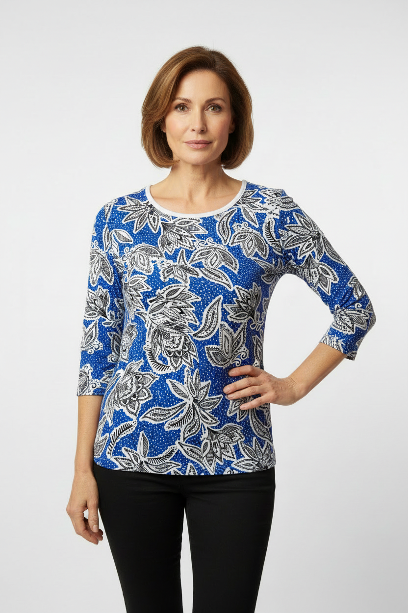 Mature model wearing blue paisley print top with white neckline trim