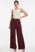 Model wearing burgundy trousers with single gold button